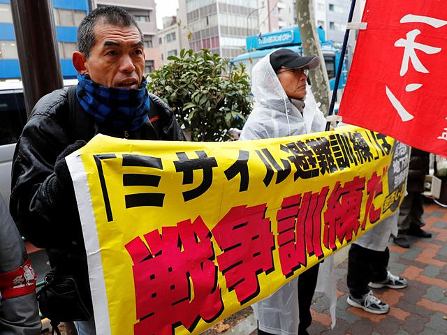 1月22日,日本东京,抗议者举着横幅阻挡假想导弹来袭防空分散演练。(新华/路透) 1月22日,日本东京,抗议者举着横幅阻挡假想导弹来袭防空分散演练。(新华/路透)