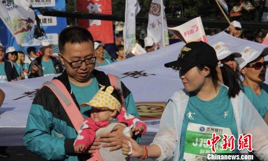 有婴儿还在背带里也与怙恃一起运动，体验“人生的第一场马拉松”。　史静静　摄