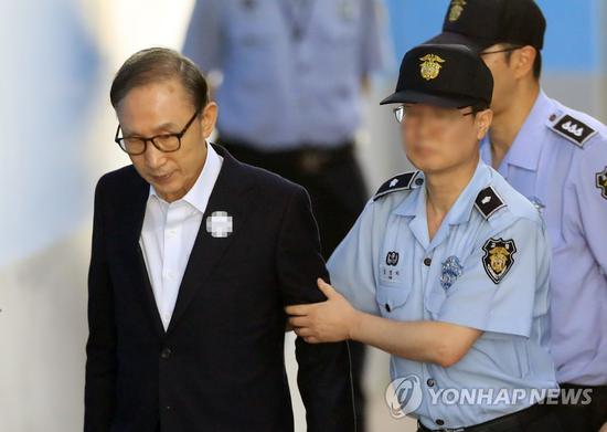 15日,李明博在狱警搀扶下行走