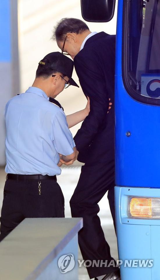 15日,李明博在狱警搀扶下走下囚车