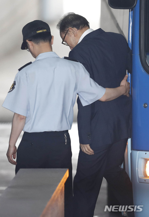 20日,在狱警搀扶下,李明博缓缓走下囚车